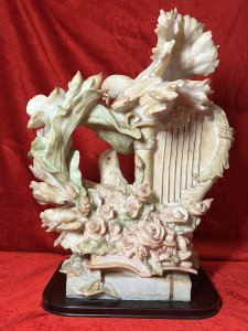 Large Italianate Romantic Turtle Doves & Instrumental Showpiece On Wood Plinth Signed Circa - 20th Century Composition - Resin Listing Description Wonderful Large Elaborate Italianate Centrepiece Depicting Pair Of Turtle Doves Entwined Amongst Musical Instruments And Vines Of Pink Roses And Pale Blue Orchids. The Turtle Doves Are Posed With One Nestled On Top Of A Strung Harp Gazing Downward At The Other Perched Upon A Whimsical Books Of Literature Next To Gilt Saxophone. An Abundance Of Flowers Flow In A Ornamental Bouquet From The Base Of The Sculpture Entwining All Elements. A Head Of Winged Cherub Is Visible Under The Top Dove On Both Front And Back Elevations. Fine Quality Hand Painted Sculpture Showpiece Can Be Admired From All Elevations. Set Upon Polished Mahogany Plinth With Front Plaque Reads 'Huda Italy' & Stamped On Back Elevation. Provenance Actual Showpiece Used As Decorative Prop In The Film 'Victoria'. Now Part of Lord Hill Museum Private Collection. For Further Information Regarding Any Of Our Stock Please Call 07376 618513 Thank-You Dimensions In Inches Height 20.5" Width 17" Depth 9"