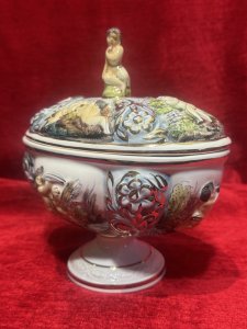 Capodimonte Ornamental Putti & Floral Spray Lidded Vase Maker - Stamped Capodimonte Composition - Porcelain Listing Description Capodimonte Porcelain Lidded Jardiniere Vase. All Sides Depicting Detailed Relief Scenes Of Cherub Figures With Shells Near The Waters Edge Surrounded By Floral Sprays, Vibrant Colour Palette With Excessive Gilt Work. Maker Stamp Capodimonte Numbered 238 On Base. Pristine Condition. Dimensions In Cms Height 21.5cm x Width 22cm X Depth 16cm