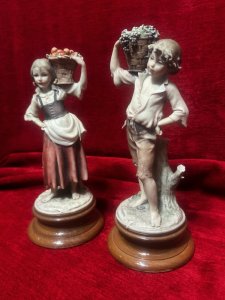Giuseppe Armani Capodimonte Pair Boy & Girl Fruit Bearer Figurines Wooden Base Circa -1982 Composition - Resin/ Wood Base Listing Description Pair Of Decorative Capodimonte Figurines Depicting Young Man and Lady Carrying Large Basket Of Fruit. Signed By Artist Giuseppe Armani And Foundry Stamped. Set On Circular Wood Plinth Bases. Dimensions In Cms Height 20cm X Width 14cm X Depth 15cm