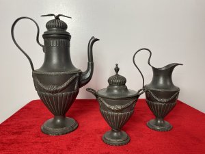 Fine Antique 18th Century KONIGSBERG Germany 3Pc Pewter Coffee Service Circa - 18th Century Composition - Pewter Elegant Fine Quality 3 Piece Pewter Coffee Service By German Makers KONIGSBERG. 3 Piece Set Comprised Of A Large Coffee Pot, Milk Jug And Sugar Bowl. The Tall Coffee Pot Has A Ornemental Dome Topped Lid, Decorated With A Soaring Eagle. The Tapered Neck Leads Into A Urn Shaped Body Decorated With Floral Garlands, Segmented Relief Pattern, Eloquent Curved Carry Handle And Elaborate Spout. The Coffee Pot Stands Upon A Circular Base With Ball And Dart Decoration And Scalloped Edge. The Milk Jug Has Matching Curved Carry Handle, Elevated Pouring Spout, With Swag Of Garlands Around Body & Set On Matching Circular Egg And Dart Base. The Lidded Sugar Bowl Has A Removable Top With Elaborate Dome And Pinnacle, Matching Garland Swags Around The Body With Curved Carry Handle And Pouring Spout. Set Upon Circular Egg And Dart Decorated Stand. Fine Quality Antique Set With All Pieces Stamped Underneath KONIGSBERG Makers Mark. Dimensions In Inches Coffee Pot Height 12" X Width 8.5"X Depth 5" Milk Jug Height 8 1/4" X Width 5 1/4" X Depth 4" Sugar Bowl Height 7.5" X Width 5.5" X Depth 4.5"