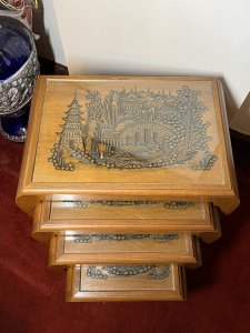 Oriental Teak Nest Of Four Tables With Mudiao Fretwork Temple Landscape Tops Circa - 1950 Composition - Teak Listing Description Set Of Four Elegant Oriental Rectangular Nesting Tables With Finely Carved Mudiao Fretwork Landscapes Under Protective Glass Tops. All Set Upon Sabre Legs With Support Stretchers. Each Table Diminishing In Size Has Oriental Village Scene With Ornate Native Trees, Elaborate Pagodas, Large Foot Bridge Over Water With Chinese Figures Crossing And Sampan Boat. Condition - Excellent Dimensions In Inches Largest Height 24.5" X Width 22" X Depth 13.5" Smallest Height 16.5" X Width13" X Depth 10.5"