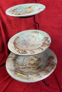 Vintage Mesa Verde Style Hand Painted 3 Tier Fruit Stand With Lizard Motifs. Circa - Vintage Composition- Earthenware / Pottery Colour Way - Blue, Teal, Gold Stunning Three Tier Metal Stand With Elegant Tripod Legs. Complete With Three Diminishing Bowls Hand Painted With Abstract Canyon Style Landscape With Ornate Gilt Lizard Motif On Each Bowl Edge. Exceptionally Decorative Piece For Fruit / Bon Bons Or Floral Display. Strong Mesa Verde National Park Tribal Influence. Dimensions In Inches Height 22” Top Bowl Diam 8” Medium Bowl Diam 11.5” Bottom Bowl 15 3/4”