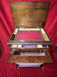 Victorian C1860 Museum Quality Burl Walnut And Marquetry Inlaid Sewing Table Circa - Period Victorian 1860 Composition - Burl Walnut With Satinwood Listing Description Finest Quality Period Victorian Antique Sewing Table/Cabinet. Elegant Burl Walnut Cabinet With Fine Floral Marquetry Inlay, Top Lid Lifts Up Revelling Red Leather Work Top With Opening Satinwood Storage & Various Compartments Surrounding For Sewing Equipment. Decorative Gladrooned Table Edge Protrudes, Underneath A Satinwood Cased Pull Out Drawer With Matching Hand Carved Balloon Shaped Handles, Containing Pin Cushions And Storage For Beads, Threads, Spools And Trinkets. Large Bottom Tier Is Pull Out Fabric/ Wool Store With Original Silk Lined Interior And Exterior. The Cabinet Stands Upon Mirrored Lyre Shaped Scroll Legs With Central Pinnacle & Looped Stretcher All Decorated With Feminine Folate Carving. Castor Wheels For Ease Of Movement. Condition - Excellent Minor Scuffs, Scratches And Usage Marks Due To Period Age Overall Condition Is Excellent. For More Information Please Call 07376 618513 Thank-you Dimensions In Inches Height 28.5" Width 24" Depth 18.5"