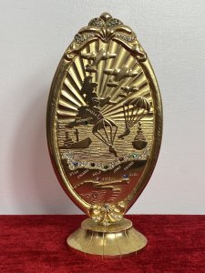 50 Year Commemorative Gold Plated Plaque Celebrating Second World War D Day Circa - 1994 Composition - Gold Plated Metal Elaborate Oval Gold Plated Plaque On Stand To Commemorate The Largest Sea Borne Invasion In History Embossed With Sea View With British Isles Outline, War Planes, Soldiers Parachuting And Fighter Bombers/Ships With Large Tank. Showing All Landmarks Of The War And Encrusted With Semi Precious Stones. Winston Churchill Quote In Tribute To The Bomber And Air Crews For They're Enormous Efforts To Establish Air Superiority Over England. ' NEVER IN THE FIELD OF HUMAN CONFLICT WAS SO MUCH OWED BY SO MANY TO SO FEW' Stamped On The Back Sterling Mint London. Provenance Purchased Directly From War Veteran, London. Dimensions In Inches Height 8" Base 3" Diameter