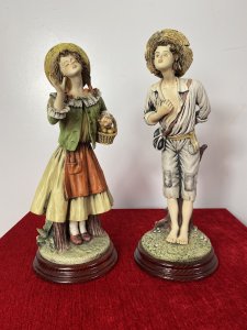 Pair Of Charming Porcelain Capodimonte Kissing Statuettes. Vintage Male And Female Pair Of Kissing Statuettes. The Lady Holds A Basket Of Oranges And Gracefully Leans In The Kiss The Male. The Male Figurine Holds A Posy Behind His Back And Leans In The Kiss His Fair Maiden. Beautiful Details, Hand Painted And Signed On The Bases. Standing On Mahogany Circular Plinths. Condition- Lovely Used Slight Damage To Finger Of Lady Otherwise Perfect Condition Dimensions In Inches Height 14 3/4” Width 5.5” Depth 5.5”