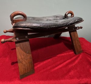 Anglo Indian Camel Stool With Brass Folate Inlays Circa - 1890 Composition - Hard Wood/ Leather Seat Listing Description Anglo Indian Camel Stool With Solid Hard Wood French Polished Frame. Leather Deep Buttoned Saddle Seat Sits Upon Triangular Pillared Legs With Handle Pinnacles For Ease Of Movement. Leg Fronts With Brass Banded Feet And Folate Inlays. Dimensions In Cms Height 42cm X Width 77cm X Depth 38cm X Seat Height 35cm