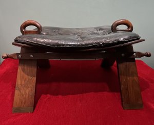 Anglo Indian Camel Stool With Brass Folate Inlays Circa - 1890 Composition - Hard Wood/ Leather Seat Listing Description Anglo Indian Camel Stool With Solid Hard Wood French Polished Frame. Leather Deep Buttoned Saddle Seat Sits Upon Triangular Pillared Legs With Handle Pinnacles For Ease Of Movement. Leg Fronts With Brass Banded Feet And Folate Inlays. Dimensions In Cms Height 42cm X Width 77cm X Depth 38cm X Seat Height 35cm