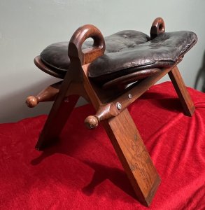 Anglo Indian Camel Stool With Brass Folate Inlays Circa - 1890 Composition - Hard Wood/ Leather Seat Listing Description Anglo Indian Camel Stool With Solid Hard Wood French Polished Frame. Leather Deep Buttoned Saddle Seat Sits Upon Triangular Pillared Legs With Handle Pinnacles For Ease Of Movement. Leg Fronts With Brass Banded Feet And Folate Inlays. Dimensions In Cms Height 42cm X Width 77cm X Depth 38cm X Seat Height 35cm
