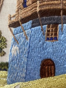 Stunning Vintage Windmill Hand Embroidered Silk Artwork Set In Glazed Frame. Circa- Vintage 1890 Composition- Hand Embroidered Silk Thread Artwork Condition - Lovely Vintage Original Beautifully Quaint And Detailed Composition Of A Large Windmill Set In Rich Flora & Forma Landscape. Rich Blue Rendered Windmill With Half Wooden Cladding Leading Up To Giant Turbines. Picturesque Details Of Wooden Door And Small Windows With Lovely Cottage Style Picket Fence & Planted Garden. Stunning Richly Coloured Composition Created Out Of Many Embroidery Stitches Which Include Straight / Back Stitch, French Knots And Running Stitches. Beautiful Example Of A Hand Embroidered Artwork Set In Glazed Wooden Frame. Dimensions In Inches Height 21.5” Width 17.5”