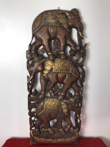 Large Hand Carved Plaque Of Balancing Trio Of Elephants In Hardwood & Gilt Work. Three Elephants Beautifully Carved With Delicate Flowers And Acanthus Vines Stand On Top Of One Another. Large Gilt Sunflower Motif As Base With Gilt Saddle Mats, Tusks, Ears And Anklets. Stunning Decorative Piece Dimensions In Inches Height 35” Width 14” Depth 1 1/4”