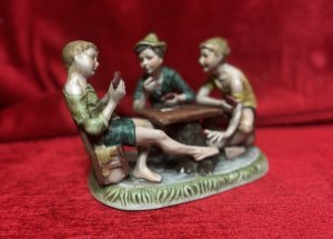 Capodimonte The Cheat’ Porcelain Sculpture Figurine Circa - 1970 Composition - Porcelain Listing Description Wonderful Iconic Capodimonte Figurine Depicting Three Boys Playing Cards, One Of The Boys Passes A Ace Of Diamonds Between His Toes To The Player Across Form Him, Hence Why The Showpiece Was Named 'The Cheat'. Original Pristine Condition. Dimensions In Cms Height 28cm X Width 19cm X Depth 14cm For Further Information Please Contact The Museum Curator On 07707 466588. Thank-you.