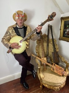 Amazing Novelty Five Piece Collection Of Country Style POP ART Strung Banjo & Lute Style Instruments Circa - Vintage Composition - Wood/Metal Individually Hand Crafted Unique Pieces With Inspiration From Historical Musical Instruments. Five Pieces Including From Left Of Pictured Line Up; 1) Indian Chieftain Banjo Circular Metal Banjo Body With Wooden Finger/Fret Board, Four Strings, Note Markers, Decorative Tuning Pegs And Indian Chief Tain Warrior Wooden Hand Painted Head And Tail Piece. Leather Carry/ Hanging Mount. Dimensions Height 46" Width14" Depth 3" 2) Junk Yard Lute Cigar Box Body With Decorative Folate Filigree Work & Air Holes, 3 Strings And Finger Board With Skeleton Keys, 'Junk Yard' Motif Head Piece. Artist Name In Scripture Lettering Steve Tomkow At The Tail. Height 39.5" Width 6.5" Depth 2" 3) 'Company Store' Cuban Male Head Lute Cuban Cigar Box Body Decorated With Foliate Filigree Work, 3 String Mounts But No Strings Currently Attached, Wooden Finger Board With Note Markers, Decorative Hand Carved Male Head Headpiece. Leather Carry\Hanging Strap. Height 50" Width 6" Depth 2.5" 4) Royal Welsh Fusileers Bugle Lute Brass Bugle Body With Royal Welsh Fusileers Emblem With Decorative Vintage Metal Rowntree's Sweet Box Centre. Two String Mounts (Currently One Attached) Finger Board With Note Markers And Gilt Filigree Work. Miniature Knife Detail At Headpiece With Leather Hanging/Carry Strap. Height 49" Width 6" Depth 4" 5) Iconic Marilyn Spanish Style Lute Spanish Cigar Box Body, Four Strings And Wooden Finger Board With Note Markers, Vintage Skeleton Key Design And Nude Female 'Marilyn' At Headpiece. Artist Scripture At Tail 'Steve Tomkow'. Leather Carry/ Hanging Strap. Height 43" Width5.5" Depth 3.5" The Country Pop Artist Steve Tomkow (Unknown) Has Created These Instruments Using Great Imagination Using Inanimate Objects To Decorate And Create The Body And Working Parts Of These Wonderful Art Piece Instruments. Each Piece Has A Particular Theme And Interest Some Junk Yard Collector Inspired And Others With Historic Influence. Really Amazing Creations By A Pop Art Genius And A Sought After Collection By Art Collectors. Being Sold As A Wall Hanging Collection. Although Some Of The Instruments Can Be Played And Plugged Into An Amplifier. We Think They Are For The Purpose Of Art Only. Perfect Showtime Collection For Wonderful Instillation In Country Bar/ Hotel, Collectors Collection Display.