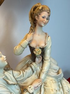 Large Italian Masterpiece ‘The Lovers Proposal’ Capodimonte Figurine Lamp. Circa - Vintage 1970s Composition- Porcelain Figurine With Light Fixture Maker - Capodimonte Breathtakingly Beautiful Capodimonte Figurine Lamp Depicting Italian Renaissance Nobility Titled ‘Young Lovers Proposal’. Finest Quality Craftsmanship In Hard Paste Porcelain Signed By Artist And Numbered (On Back). Sitting Male And Swooning Female Perched On Ornamental Chair. Dressed In Garments Of Nobility With Fine Silks And Laces Delicately Recreated In Porcelain. With Powdered Wigs, Intricate Facial Details And Expressions. Charming Ukulele Instrument Lies Face Down Upon The Floor Laden With Delicate Flowers. Ornamental Elaborate Pink Shade With Pink Fringing. Stands Upon Wooden Base With Brass Feet. Fitted With U.K. 3 Prong Plug. This Truly Stunning Piece Tells A Truely Romantic Story. This Elegant Lamp Would Be Perfect For A Boudoir, Lounge Or Living Area A Real Talking Point. Condition- Perfect Figurine No Damage. Light Working Dimensions In Inches Overall Height 27” Figurine Height 13” Figurine Width 10.5” Figurine Depth 6.5” Base Width11 1/4” Base Depth 9.5”