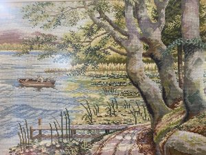Hand Woven Lake Windermere Landscape Tapestry With Fisherman In Rowing Boat Circa - 20th Century Vintage Composition - Wool Work Intricate Woodwork Tapestry With Stunning Lake View Showing Fisherman Patiently Sitting In A Rowing Boat With His Fishing Rod Perched. The Lake Surrounded By Reeds, Lilly Pads And Water Daisies With Narrow Track To The Right With Detailed Trees And Jetty. Lovely Charming Subject With Stunning Perspective In A Array Of Vibrant Yellow, Green, And Blue Hues. Lake Scene Thought To Be At Lake Windermere. Framed / Unsigned Dimension In Inches Height 25.5" Width 31 1/4"