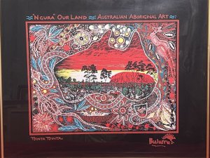 Australian Bulurru Aboriginal Artwork Titled - "NGURA" OUR LAND Artist - TJINTA TJINTA Listing Description Wonderful Vibrant Aboriginal Artwork Of Great Cultural Significance. The Central Portion Of The Artwork Shows The Sacred Uluru/ Ayers Rock, Which Is One of Australias Most Recognised Landmarks. The Rock Is A Colossal Sandstone Formation Standing 348M High, Rising 863M Above Sea Level. Uluru Is Noted for Appearing To Change Colour At Different Times Of the Day, Most Noticeably Glowing Red At Dawn And Sunset. Entwined Around the Artwork Are Native Animals, Including Kangaroos, Snakes, Lizards, Turtles As Well As Native Fruits And Forna. Glazed And Framed Original Artwork. Print On Canvas. Dimensions In Cm Height 48cm X Width 57.5cm