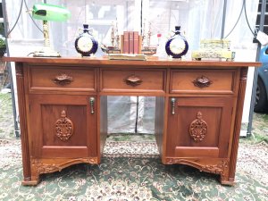 Famous Admiral Lord Nelson Style Admirality Office Desk In Solid Teak Wood. Admiralty Desk With 3 Pull Out Drawers And 2 Opening Cupboard Doors. Cupboards With Shelf Inside For Book, Map And Document Storage. Carved Column Pilasters On The Front With Ornate Plaque Carvings of Acanthus Leaves On Both Cupboard Doors And Ornate Carved Flora And Forna Handles On The Pull Out Drawers. Stands Upon Regency Brass Castor Feet. Exceptionally Solid Thick Teak Top Heavy And Stunning Quality Piece. Dimensions In Inches Height 33.5” Width 58.5” Depth 21.5 Kneehole Height From Floor 25” Kneehole Width 16”