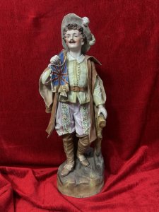 Parian Hand Painted Bisque Cavalier Figurine Holding Britannia Flag Circa - 1890 Composition - Hard Paste Porcelain Listing Description Exceptional Parian Figurine Of Gentleman Cavalier Extravagantly Dressed Hat With Feather Plumes, Lemon Belted Front Buttoned Shirt, Pink Floral Pantaloons, Cape And Brown Leather Knee High Boots. Cavalier Holds British Ensign Flag With Gilt Tassels In Right Hand. Condition - Excellent Antique Figurine Showing Age Cracks In Porcelain. Dimensions In Cms Height 52cm X Width 20cm X Depth 18cm Base 17cm SQ For Further Information Please Call The Museum Curator On 07707 488566 Thank-you.