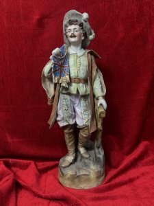 Parian Hand Painted Bisque Cavalier Figurine Holding Britannia Flag Circa - 1890 Composition - Hard Paste Porcelain Listing Description Exceptional Parian Figurine Of Gentleman Cavalier Extravagantly Dressed Hat With Feather Plumes, Lemon Belted Front Buttoned Shirt, Pink Floral Pantaloons, Cape And Brown Leather Knee High Boots. Cavalier Holds British Ensign Flag With Gilt Tassels In Right Hand. Condition - Excellent Antique Figurine Showing Age Cracks In Porcelain. Dimensions In Cms Height 52cm X Width 20cm X Depth 18cm Base 17cm SQ For Further Information Please Call The Museum Curator On 07707 488566 Thank-you.