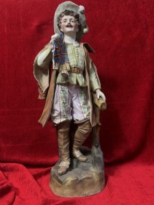 Parian Hand Painted Bisque Cavalier Figurine Holding Britannia Flag Circa - 1890 Composition - Hard Paste Porcelain Listing Description Exceptional Parian Figurine Of Gentleman Cavalier Extravagantly Dressed Hat With Feather Plumes, Lemon Belted Front Buttoned Shirt, Pink Floral Pantaloons, Cape And Brown Leather Knee High Boots. Cavalier Holds British Ensign Flag With Gilt Tassels In Right Hand. Condition - Excellent Antique Figurine Showing Age Cracks In Porcelain. Dimensions In Cms Height 52cm X Width 20cm X Depth 18cm Base 17cm SQ For Further Information Please Call The Museum Curator On 07707 488566 Thank-you.