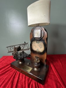 Louis Blériot French Aviation Inventor Showpiece Lamp/Timepiece Circa - 1960's Composition - Wood With Mixed Metals Brief History Of Aviation Inventor Louis Blériot 1st July 1872- 1 August 1936 Bleroit, a graduate of the École Centrale in Paris, Met and married Alice Vedéne while performing military service as a lieutenant of artillery. He used his modest fortune , amassed as a manufacturer of headlamps and other automotive accessories, to fund his earliest work in aeronautics. Following a series of experiments with a towed glider on the Seine River, He built and tested a variety of powered aircraft ranging from box-kite biplanes to a tail first (canard) monoplane. On July 25, 1909, Blériot piloted his Blériot XI, a monoplane with a 25 horse power engine, across the English Channel from Calais, France, To Dover, England. This feat won him a prize of £1,000 offered by the London Daily Mail and resulted in his emergence as one of the leading aircraft pilots and manufactures of the era. Between 1909 and the beginning of World War I in August 1914, the Blériot factory produced more than 800 aircraft, many of them type XI Monoplanes or variants of that design. Listing Description Wonderful Commemorative Showpiece Celebrating Louis Blériot's Crossing Over The English Channel In July 25th 1909. Solid Oak Wood Sculptural Masterpiece Showcasing A Large Bléroit's XI Plane Hand Crafted In Iron Work With Blétriot Aboard Piloting. A Iron Eagle Mascot Set Upon Wood Pinnacle, Bestowing Hope, Freedom And Courage To Look Ahead. A Wooden Arch With Timepiece Complete With An Eight Day Movement And Lamp Fitting With Original Oval Shade. This Original French Showpiece Hs Previously Been Fitted With British Plug. *This is an Antique item. We kindly advise you have all electrical items PAT Tested before use in your home* Dimension In Inches Height 23 1/4" X Base Width15" X 7" X Depth 13" including plane structure.