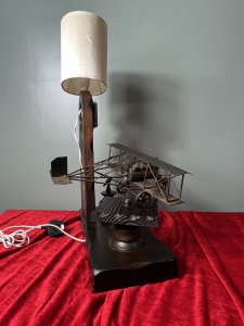 Louis Blériot French Aviation Inventor Showpiece Lamp/Timepiece Circa - 1960's Composition - Wood With Mixed Metals Brief History Of Aviation Inventor Louis Blériot 1st July 1872- 1 August 1936 Bleroit, a graduate of the École Centrale in Paris, Met and married Alice Vedéne while performing military service as a lieutenant of artillery. He used his modest fortune , amassed as a manufacturer of headlamps and other automotive accessories, to fund his earliest work in aeronautics. Following a series of experiments with a towed glider on the Seine River, He built and tested a variety of powered aircraft ranging from box-kite biplanes to a tail first (canard) monoplane. On July 25, 1909, Blériot piloted his Blériot XI, a monoplane with a 25 horse power engine, across the English Channel from Calais, France, To Dover, England. This feat won him a prize of £1,000 offered by the London Daily Mail and resulted in his emergence as one of the leading aircraft pilots and manufactures of the era. Between 1909 and the beginning of World War I in August 1914, the Blériot factory produced more than 800 aircraft, many of them type XI Monoplanes or variants of that design. Listing Description Wonderful Commemorative Showpiece Celebrating Louis Blériot's Crossing Over The English Channel In July 25th 1909. Solid Oak Wood Sculptural Masterpiece Showcasing A Large Bléroit's XI Plane Hand Crafted In Iron Work With Blétriot Aboard Piloting. A Iron Eagle Mascot Set Upon Wood Pinnacle, Bestowing Hope, Freedom And Courage To Look Ahead. A Wooden Arch With Timepiece Complete With An Eight Day Movement And Lamp Fitting With Original Oval Shade. This Original French Showpiece Hs Previously Been Fitted With British Plug. *This is an Antique item. We kindly advise you have all electrical items PAT Tested before use in your home* Dimension In Inches Height 23 1/4" X Base Width15" X 7" X Depth 13" including plane structure.