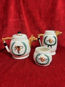 Gentlemen's British Hunt Scene Portland Pottey Tea Service Circa - 1940 Composition - Ceramic Listing Description British Fox Hunting Gentlesman's Tea Service. Complete With Tea Pot , Cream Jug And Sugar Bowl. Both Teapot And Jug With Fox Head Spouts. All Pieces Complete With Red Coat Hunt Master On Horse Back With Red Foxes On Front Elevations With Wreath And Decorative Hunt Design On Reverse. Condition - V Good Signs Of Wear To Glaze. Dimensions in Cms Teapot Cream Jug Sugar bowl