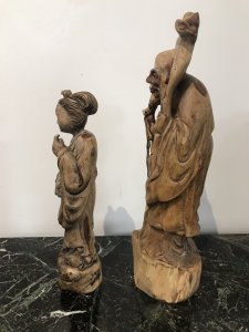 Two Oriental Fruitwood Carvings One Female With Fine Carved Robe Details Holding Flowers One Large Male Carving With Unusual Long Carved Hair And Flowing Robe Origin Unknown Presumed To Be Chinese Collectors Items Dimensions In Inches Male Height 15” Width 4” Female Height 12” Width 3.5”