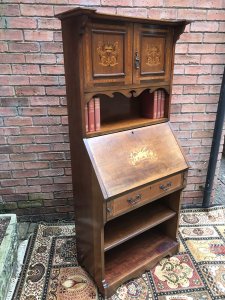 Fine Red Walnut Arts And Crafts Secretaire Bookcase Shaped Top Pediment With Double Doors For Book Storage Drop Down Front With Pull Out Supports Displaying Stunning Satinwood And Pewter Inlays Of Musical Instruments And Foliage Shelves Under Pull Out Drawer Red Walnut Cabinet With With Oak Lined Drawer Delightful Item In Beautiful Condition With Original Key Dimensions In Inches Height 65” Width 28” Depth 15”