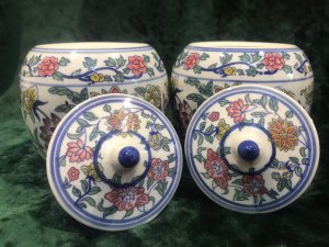 Pair Of Reproduction Kang Sing Style Porcelain Lidded Ginger Jars Composition- Porcelain Circa- Vintage Reproduction Pair Lidded Bulbas Ginger Jars With Domed Top And Delicate Handle Richly Decorated With Native Chinese Lotus Flowers And Chinese Blossoms White Glaze Jars With Rich Blue, Pink, Red, Yellow And Green Hues Chinese Markings On The Bases Lovely Examples Of Sought After Chinese Vases Dimensions In Inches Height 5.5” Width 5” Circumference 15” Widest Point
