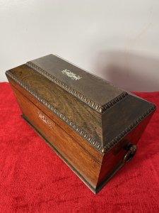 William IIII Rosewood Sarcophagus Shaped Tea Caddy With Mother Of Pearl Inlay Beautiful Solid Rosewood Tea Caddy Chest With Egg And Dart Gadrooned Top Edge With Mother Of Pearl Inlay Floral Motifs On The Top Lid ( Monogramed R.H.B) And Around Lock. Each Side Bears Drop Ring Handles. (One Missing) Inside The Chest There Are Two Hinged Top Compartments For Tea And A Circular Slot For Mixing Bowl Or Drinking Flask. Stunning Rich Patina Antique Tea Chest. Dimensions In Inches Height 8” Width 13” Depth 6”