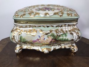 Stunning Object Of Virtue Marie Antoinette Sevres Style Porcelain Trinket Casket. French Origin Bombay Shaped Porcelain Jewellery/Trinket Casket Profusely Hand Painted With Panels Of Putti With Flora And Forna Painted In Stunning Cartouches Bronze Hinged Lid With Bronze Closing Clasp In Leaf Work With Reposed Cherubs In Landscape Stands Upon Four Shaped Cabriole Legs Heavily Gilded Grand Tour Quality Specimen Delivery By Our Butler To Your Door UK Same Day If Desired. Provenance Purchased From Chateau In Paris From Baron Dupree 1973 Dimensions In Inches Height 9.5” Width 13.5” Depth 11”