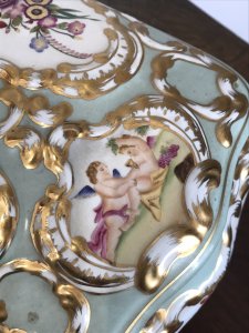 Stunning Object Of Virtue Marie Antoinette Sevres Style Porcelain Trinket Casket. French Origin Bombay Shaped Porcelain Jewellery/Trinket Casket Profusely Hand Painted With Panels Of Putti With Flora And Forna Painted In Stunning Cartouches Bronze Hinged Lid With Bronze Closing Clasp In Leaf Work With Reposed Cherubs In Landscape Stands Upon Four Shaped Cabriole Legs Heavily Gilded Grand Tour Quality Specimen Delivery By Our Butler To Your Door UK Same Day If Desired. Provenance Purchased From Chateau In Paris From Baron Dupree 1973 Dimensions In Inches Height 9.5” Width 13.5” Depth 11”