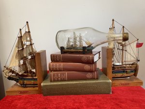 Cutty Sark Merchant Ship Model On Stand Hand Crafted Piece . Beautiful Hand Painted Ships Model Of The British Cutty Sark Tea Clipper Ship Sailing On Blue Seas. Signed By Maker D Voisey In The Neck Of The Bottle And Dated 1967. With Gold Cap And Wooden Stand History The Cutty Sark Is A British Tea Clipper Sailing Ship Of The Victorian Era. Designed By Hercules Linton And Built On The Banks Of The River Levon In Dumbarton Scotland In 1869 By Willis And Sons Ship Owners. Over The Course Of Her Sea Fairing Career She Successfully Navigated Eight Return Voyages From London To China With A Cargo Of Tea. Dimensions In Inches Height 4.5” Width 11.5” Depth 4.5”