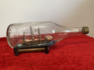 Cutty Sark Merchant Ship Model On Stand Hand Crafted Piece . Beautiful Hand Painted Ships Model Of The British Cutty Sark Tea Clipper Ship Sailing On Blue Seas. Signed By Maker D Voisey In The Neck Of The Bottle And Dated 1967. With Gold Cap And Wooden Stand History The Cutty Sark Is A British Tea Clipper Sailing Ship Of The Victorian Era. Designed By Hercules Linton And Built On The Banks Of The River Levon In Dumbarton Scotland In 1869 By Willis And Sons Ship Owners. Over The Course Of Her Sea Fairing Career She Successfully Navigated Eight Return Voyages From London To China With A Cargo Of Tea. Dimensions In Inches Height 4.5” Width 11.5” Depth 4.5”