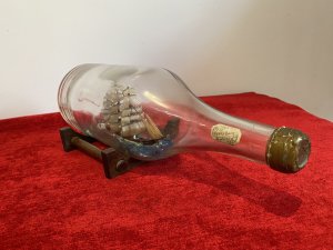 Cutty Sark Merchant Ship Model On Stand Hand Crafted Piece . Beautiful Hand Painted Ships Model Of The British Cutty Sark Tea Clipper Ship Sailing On Blue Seas. Signed By Maker D Voisey In The Neck Of The Bottle And Dated 1967. With Gold Cap And Wooden Stand History The Cutty Sark Is A British Tea Clipper Sailing Ship Of The Victorian Era. Designed By Hercules Linton And Built On The Banks Of The River Levon In Dumbarton Scotland In 1869 By Willis And Sons Ship Owners. Over The Course Of Her Sea Fairing Career She Successfully Navigated Eight Return Voyages From London To China With A Cargo Of Tea. Dimensions In Inches Height 4.5” Width 11.5” Depth 4.5”