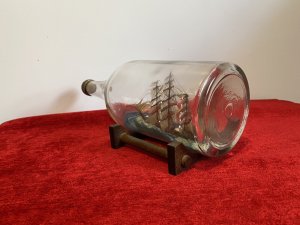 Cutty Sark Merchant Ship Model On Stand Hand Crafted Piece . Beautiful Hand Painted Ships Model Of The British Cutty Sark Tea Clipper Ship Sailing On Blue Seas. Signed By Maker D Voisey In The Neck Of The Bottle And Dated 1967. With Gold Cap And Wooden Stand History The Cutty Sark Is A British Tea Clipper Sailing Ship Of The Victorian Era. Designed By Hercules Linton And Built On The Banks Of The River Levon In Dumbarton Scotland In 1869 By Willis And Sons Ship Owners. Over The Course Of Her Sea Fairing Career She Successfully Navigated Eight Return Voyages From London To China With A Cargo Of Tea. Dimensions In Inches Height 4.5” Width 11.5” Depth 4.5”