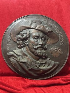 Circa - 19th Century Composition - Beaten Copper Large Copper Wall Plaque Depicting Flemish Baroque Painter Sir Peter Paul Ruben’s Classical Relief Portrait Showing Artist Peter Paul Ruben’s At The Tome The Plaque Was Created Wearing A Large Tassel Hat And Oversized Lace Collar. The Artist Gazes To The Right. A Decorative Coat Of Arms Placed Near The Face And Artist Ruben’s Name In Latin Scripture Inscribed Around The Top Edge. Stunning Craftsmanship A Wonderful Historic Showpiece. Dimensions In Inches Height 25.5” X Depth From Wall 2”