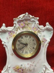 Antique German Dresden mantel clock, circa 1880, crafted from white hard-paste porcelain and decorated with spring floral bouquets and gilt border detailing. Features a machined silver clock face and a seven-day movement. Numbered on the base. Dimensions: 16 cm high × 13 cm wide × 6.5 cm deep. Clock face diameter: 6.5 cm.