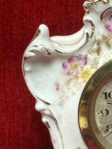 Antique German Dresden mantel clock, circa 1880, crafted from white hard-paste porcelain and decorated with spring floral bouquets and gilt border detailing. Features a machined silver clock face and a seven-day movement. Numbered on the base. Dimensions: 16 cm high × 13 cm wide × 6.5 cm deep. Clock face diameter: 6.5 cm.