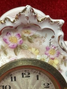 Antique German Dresden mantel clock, circa 1880, crafted from white hard-paste porcelain and decorated with spring floral bouquets and gilt border detailing. Features a machined silver clock face and a seven-day movement. Numbered on the base. Dimensions: 16 cm high × 13 cm wide × 6.5 cm deep. Clock face diameter: 6.5 cm.