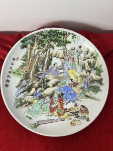 Large Porcelain Chinese Charger Plate With Ornate Celebratory Family Gathering Circa - 20th Century Vintage Composition - Porcelain Large Circular Decorative Porcelain Chinese Charger Plate With Hand Painted Scene Of A Intricate Family Celebratory Gathering Which Includes Twelve Figures Set Amongst Rocky Hillside Adorned With Oriental Trees. Some Figures Sit Playing Board Games, Reading Scriptures And Some Stand In Deep Conversation. A Young Female Carries A Laden Fruit Bowl Whilst Another Prepares Tea And Soup. Amazing Detail Of Finely Painted Faces, Hair And Hands With Wonderful Execution Of Oriental Costumes In Over Layered Fabric Kimonos And Fine Pattern In Bright Colours. Signed By Artist Front And Back. Dimensions In Inches Plate Diameter 13.5" Height From Table Top 1/2"