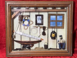 Intriguing Shipwright Diorama Model. Circa - Vintage Composition - Wood/Resin And Glass Unique Framed Diorama Model Of Shipwrights Workshop. Beamed Roof Workshop Display Showcasing Hoist Propping Up Ships Sails. Portrait Picture Set Upon The Wall Of Shipwright, The Actual Man In The Pictured Sits On A Chair With Ships Model In His Arms. An Array Of Shipping Rope Hangs On The Wall With Ships Lantern And Other Shipwright Tools. A Window View With Lighthouse In The Distance. Lovely Piece For Study Wall Of Nautical Enthusiast . Dimensions In Inches Height 11” Width 15”