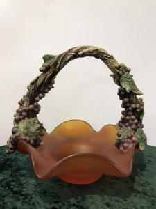 French Reproduction Ornate Grape Vine Handle Orange Art Glass Fruit Bowl Porcelain Grape Vine Handle With Purple Fruit And Green Vine Leaves With Stunning Shaped Burnt Orange Frosted Glass Fruit Bowl Decorative Item Pristine Condition Dimensions In Inches Height 11” Width 12”