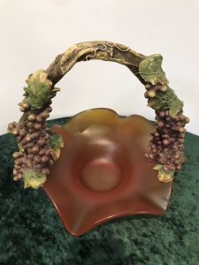 French Reproduction Ornate Grape Vine Handle Orange Art Glass Fruit Bowl Porcelain Grape Vine Handle With Purple Fruit And Green Vine Leaves With Stunning Shaped Burnt Orange Frosted Glass Fruit Bowl Decorative Item Pristine Condition Dimensions In Inches Height 11” Width 12”