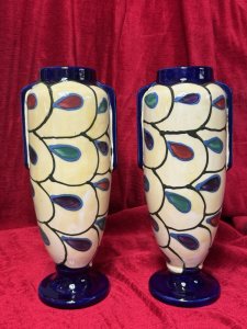 Pair Of Art Deco Ditmar Urbach Czechoslovakian Art Pottery Vases Listing Description Exceptional Sought After Period Art Deco Ditmar Urbach Art Pottery Vases. A Czechoslovakian Art Pottery Company Best Known For Decorative Pieces In The Art Deco Style, Their Primary Production Period During 1920-1930, With A Focus On Hand Painted, Distinctive Forms And Unique Sculptural Pieces. These Art Pottery Pieces Are now Highly Collectable Amongst Collectors Of The Art Deco Period. This Pair Of Tall Vases Showcase A Geometric Style Pattern Of Stylised Teardrop Shaped Motifs, In Plum, Blue And Green With Cream Body And Dark Blue Mouth And Base. Both Have Matching Markings On The Base. Stunning Original Condition. Kindly Call The Museum Curator For More Information On 07707 488566 Thank-you. Dimensions In Cms. Height 29cm x Width 13cm x Mouth 6.5cm x Base 9cm