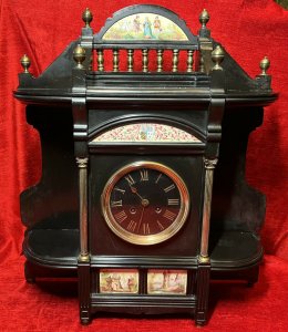 Rare Historic French Aristocracy Aesthetic Movement Timepiece Circa - 19th Century 1880 Composition - Slate/ Brass/ Porcelain Listing Description Impeccable Museum Quality French Aesthetic Movement Timepiece. A Wonderfully Decorative Architectural Clock In A Medieval Temple Shape. The Top Section Has A Stepped Platform For Display Of Decorative Curiosities, With Elaborate Six Pillared Brass Finial Mounts. The Central Portion Showcases A Half Moon Porcelain Plaque With Painted Aristoractic Figures In Clothing Of The Period Which Sits Directly Above A Brass Banister Frieze. Underneath The Platform A Hand Painted Enamel Artwork With The Original French Family Coat Of Arms With Acanthus Leaf And Mistletoe Sprays. A Circular Black Enamel Clock Face With Gilt Roman Numeral Dial Encased Either Side By Ornate Brass Corinthian Pillars And Surrounding Corner Shelve Mounts (Also For Decorative Display). A Elegant Base Section With Central Plaques Of French Castle And Landscape Scenes Standing Upon Six Bun Feet. Integral 8 Day Movement Complete With Original Winding Key And Pendulum. Condition - Very Good Clock Case Showing Minor Signs Of Wear. Scuffs, Scratches & Minor Chips Visible Conducive To Age And Usage. Movement In Good Working Order. Dimensions In Inches Height 21.5" Width 19" Depth6"