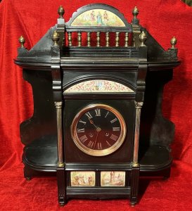 Rare Historic French Aristocracy Aesthetic Movement Timepiece Circa - 19th Century 1880 Composition - Slate/ Brass/ Porcelain Listing Description Impeccable Museum Quality French Aesthetic Movement Timepiece. A Wonderfully Decorative Architectural Clock In A Medieval Temple Shape. The Top Section Has A Stepped Platform For Display Of Decorative Curiosities, With Elaborate Six Pillared Brass Finial Mounts. The Central Portion Showcases A Half Moon Porcelain Plaque With Painted Aristoractic Figures In Clothing Of The Period Which Sits Directly Above A Brass Banister Frieze. Underneath The Platform A Hand Painted Enamel Artwork With The Original French Family Coat Of Arms With Acanthus Leaf And Mistletoe Sprays. A Circular Black Enamel Clock Face With Gilt Roman Numeral Dial Encased Either Side By Ornate Brass Corinthian Pillars And Surrounding Corner Shelve Mounts (Also For Decorative Display). A Elegant Base Section With Central Plaques Of French Castle And Landscape Scenes Standing Upon Six Bun Feet. Integral 8 Day Movement Complete With Original Winding Key And Pendulum. Condition - Very Good Clock Case Showing Minor Signs Of Wear. Scuffs, Scratches & Minor Chips Visible Conducive To Age And Usage. Movement In Good Working Order. Dimensions In Inches Height 21.5" Width 19" Depth6"