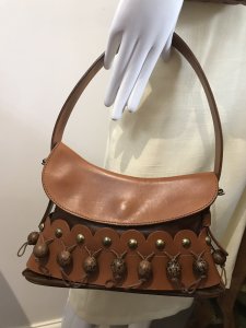 Stunning Rodo Designer Scalloped Edge Tan Leather Pom Pom Handbag Gorgeous Wooden Pom Poms On Waxed Cotton Cords All Around The Front Along A Scalloped Edge Decorated With Brass Studs Quality Thick Leather With Decorative Top Stitching Lovely Sturdy Handle With Belt Buckle Design Both Sides Magnetic Clasp Closure Absolutely Stunning Inside Is Still Stuffed With Original RODO Tissue Paper Almost New A Few Minor Marks From Storage Lovely Condition Really Unusual Designer Handbag Inspired By The Rodeo These Bags Are Very Expensive New And Are Hand Crafted In Italy From The Finest Leathers Dimensions In Inches Bag Height 7.5” Bag width 11” Bag Height with Handle Extended 13” Depth 2.5”