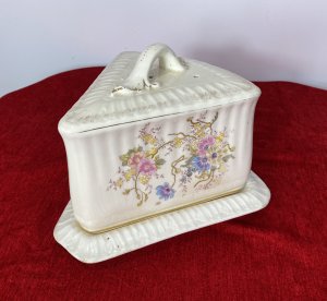 Victorian Royal Dolton Triangular Cheese Wheel Comport Dish & Cover. Circa -1870 Triangular Wedge Shaped Large Cheese Dish Comprising Of Lift Up Lid With Ornate Handle. Decorated With Sprays Of Meadow Flowers In Pastel Pink, Blue And Yellow Hues. Wedge Shaped Cheese Tray Showing Signs Of Age With Marks In Glaze From Usage. Holes In Lid To Allow Cheese To Air. Stunning Conversation Piece And A Beautiful Example Of Antique Victorian Royal Dolton. Clearly Marked On Bass And Inside Lid. Condition- Antique Used No Damage Cracks Visible In Glaze Only Due To Age And Wear Marks On Cheese Tray Base Please See Images. Dimensions In Inches Height 8” Width 11” Length 9.5”