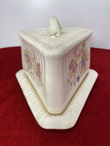 Victorian Royal Dolton Triangular Cheese Wheel Comport Dish & Cover. Circa -1870 Triangular Wedge Shaped Large Cheese Dish Comprising Of Lift Up Lid With Ornate Handle. Decorated With Sprays Of Meadow Flowers In Pastel Pink, Blue And Yellow Hues. Wedge Shaped Cheese Tray Showing Signs Of Age With Marks In Glaze From Usage. Holes In Lid To Allow Cheese To Air. Stunning Conversation Piece And A Beautiful Example Of Antique Victorian Royal Dolton. Clearly Marked On Bass And Inside Lid. Condition- Antique Used No Damage Cracks Visible In Glaze Only Due To Age And Wear Marks On Cheese Tray Base Please See Images. Dimensions In Inches Height 8” Width 11” Length 9.5”